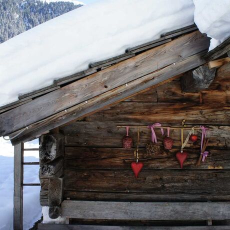 Eine Hütte aus Holz mit einem halben Meter Schnee auf dem Dach