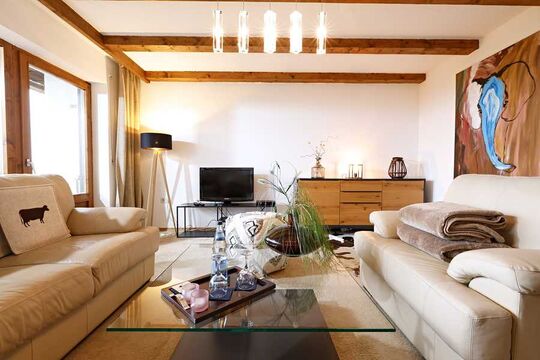 TV and chest of drawers in the living room of the hotel's own vacation apartment in Kierwang with plenty of natural light from the panoramic window