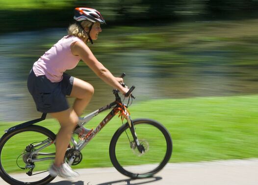 A cyclist on a mountain bike on a flat cycle path next to a river