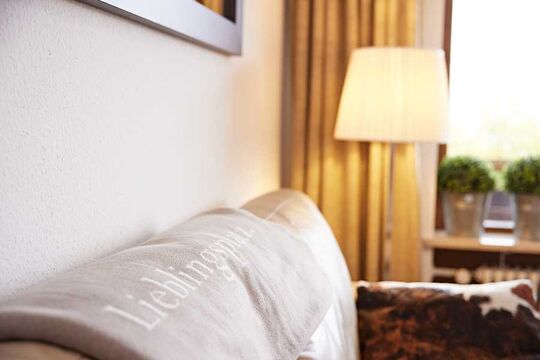 Close-up of a woolen blanket with the inscription Favorite place with floor lamp in the background in the hotel's own vacation apartment
