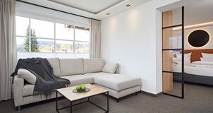 Living area with sofa and blanket above in a hotel room with the sleeping area in the background