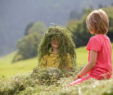 Two small children playing in the freshly mown hay