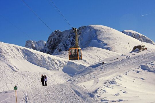 A winter hiking trail on the Nebelhorn with two hikers and the cable car in the background