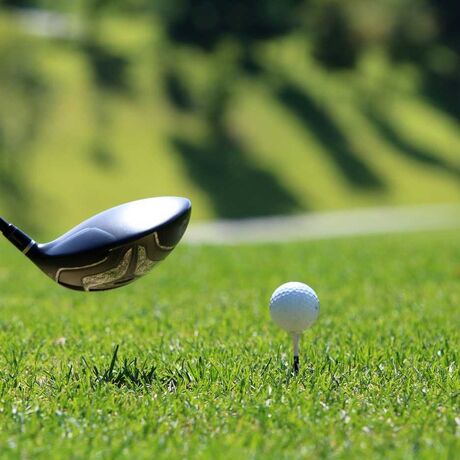 Ein Golfschläger und ein Golfball auf einem Tee