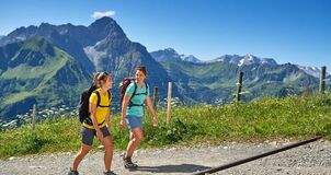 Two female hikers on a hiking trail at high altitude with the Allgäu Alps in the background