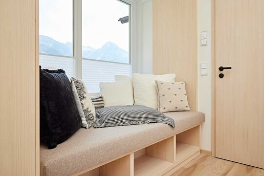 Entrance area with sitting area in the Widderstein hotel room decorated with pillows and view outside