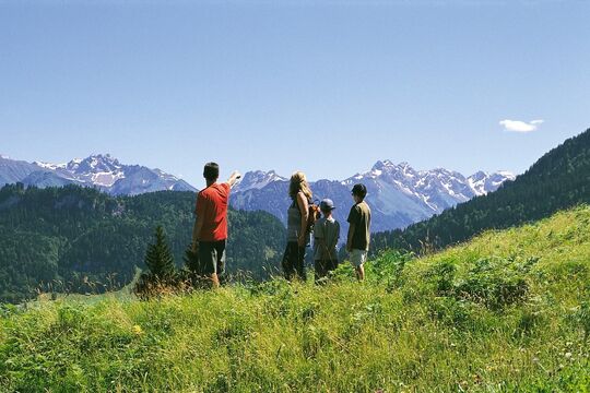 Parents with two children hiking at altitude looking at the mountain panorama in the distance