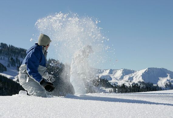 Two people playing in the fresh snow and throwing snow at each other