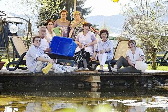 The housekeeping team sits on the wooden veranda by the pond