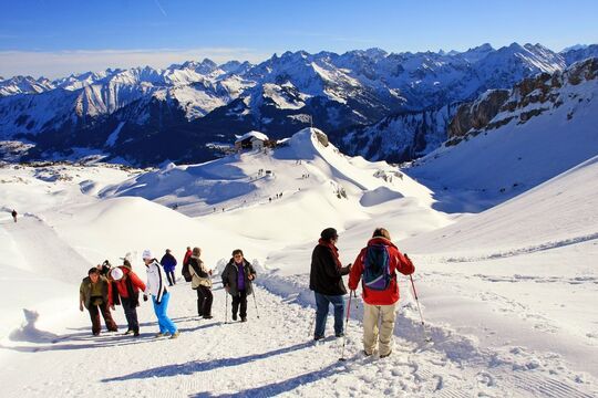 A winter hiking trail with hikers on a beautiful winter's day with bright sunshine and the mountain panorama in the background