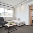 Living area with sofa and blanket above in a hotel room with the sleeping area in the background