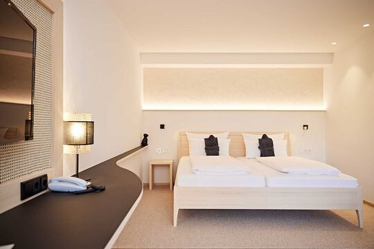 Double bed in the Widderstein room with two bathrobes, positioned in front of the pillows
