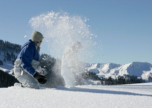 Two people playing in the fresh snow and throwing snow at each other