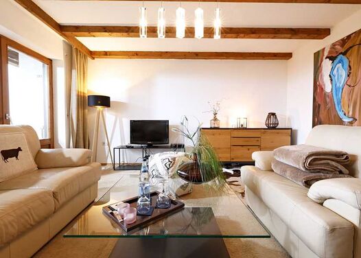 TV and chest of drawers in the living room of the hotel's own vacation apartment in Kierwang with plenty of natural light from the panoramic window