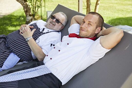 Two chefs lying on a daybed in the garden