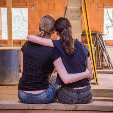 Two women holding each other and sitting on a bench