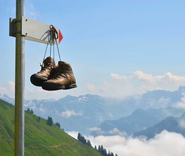 A pair of mountain boots, hung by their laces from a signpost