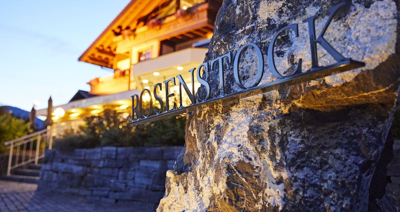 Fels mit Rosenstock Schriftzug aus Metall, der vor dem Hotel als Hotelschild steht