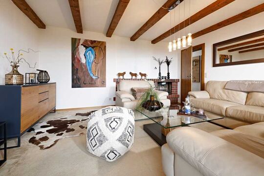 Seating area in the living room of the hotel's own vacation apartment in Kierwang with plenty of natural light through the large panoramic window